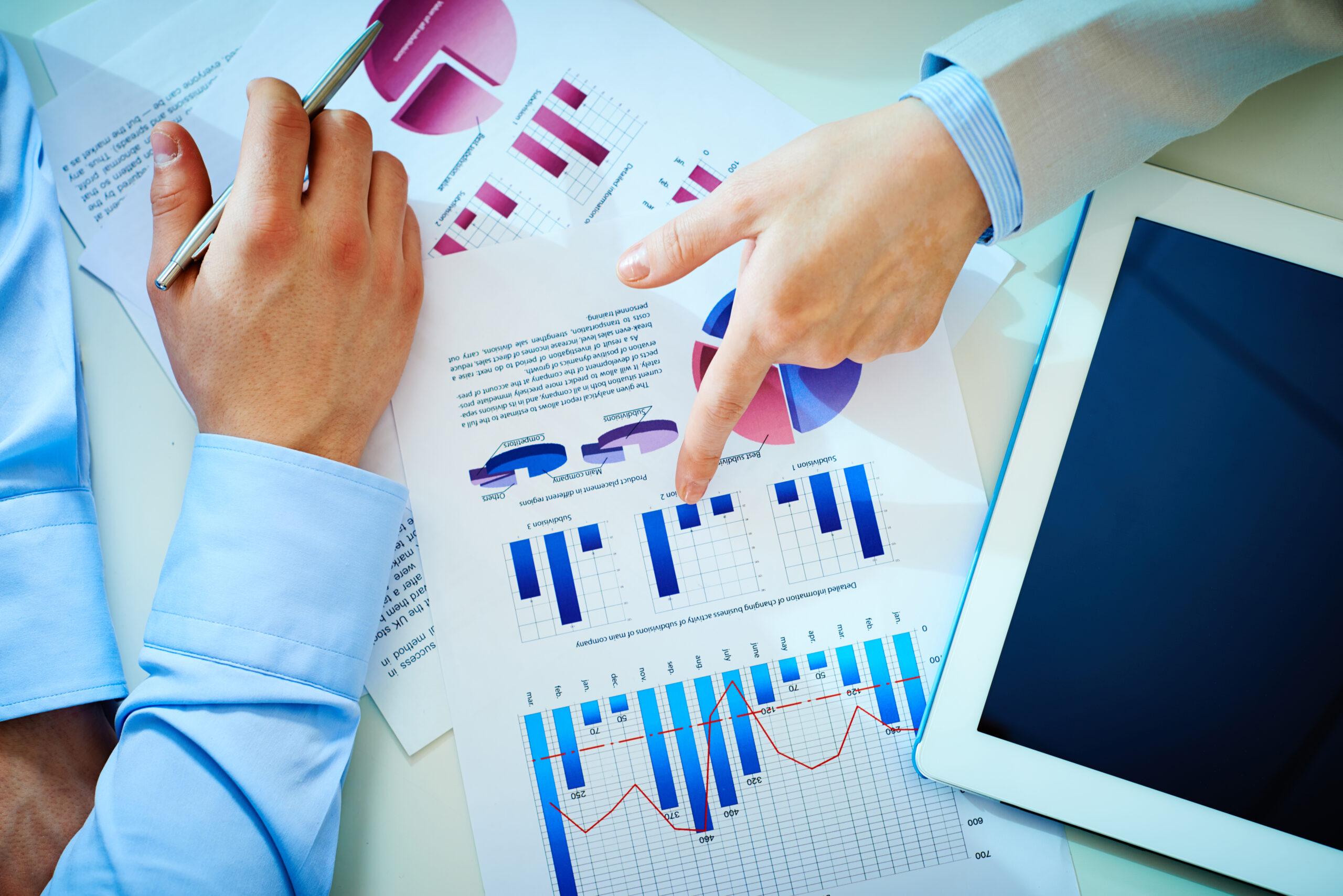 Close-up of female hand pointing at business document while explaining chart